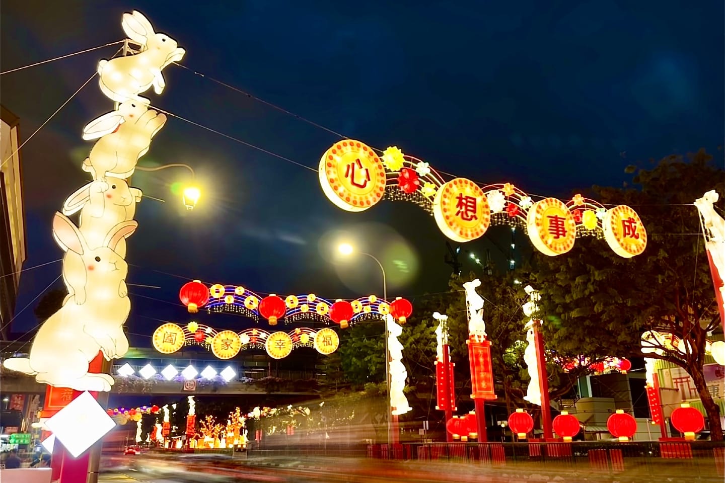 Night view of street decorations with illuminated rabbits, lanterns, and Chinese text.